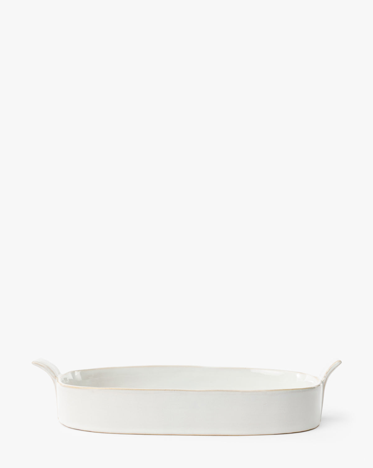 The 1.5 Quart Stoneware Baker is a white ceramic oval dish with two side handles, ideal for oven-to-table serving and shown on a plain white background by McGee & Co.