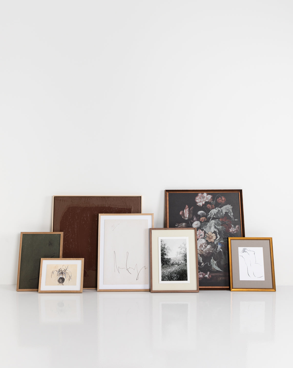 Six Bare framed art prints, crafted with gallery-quality materials, are displayed side by side on a plain white wall. The set features minimalistic outline art, a floral painting, and a black-and-white nature photograph.