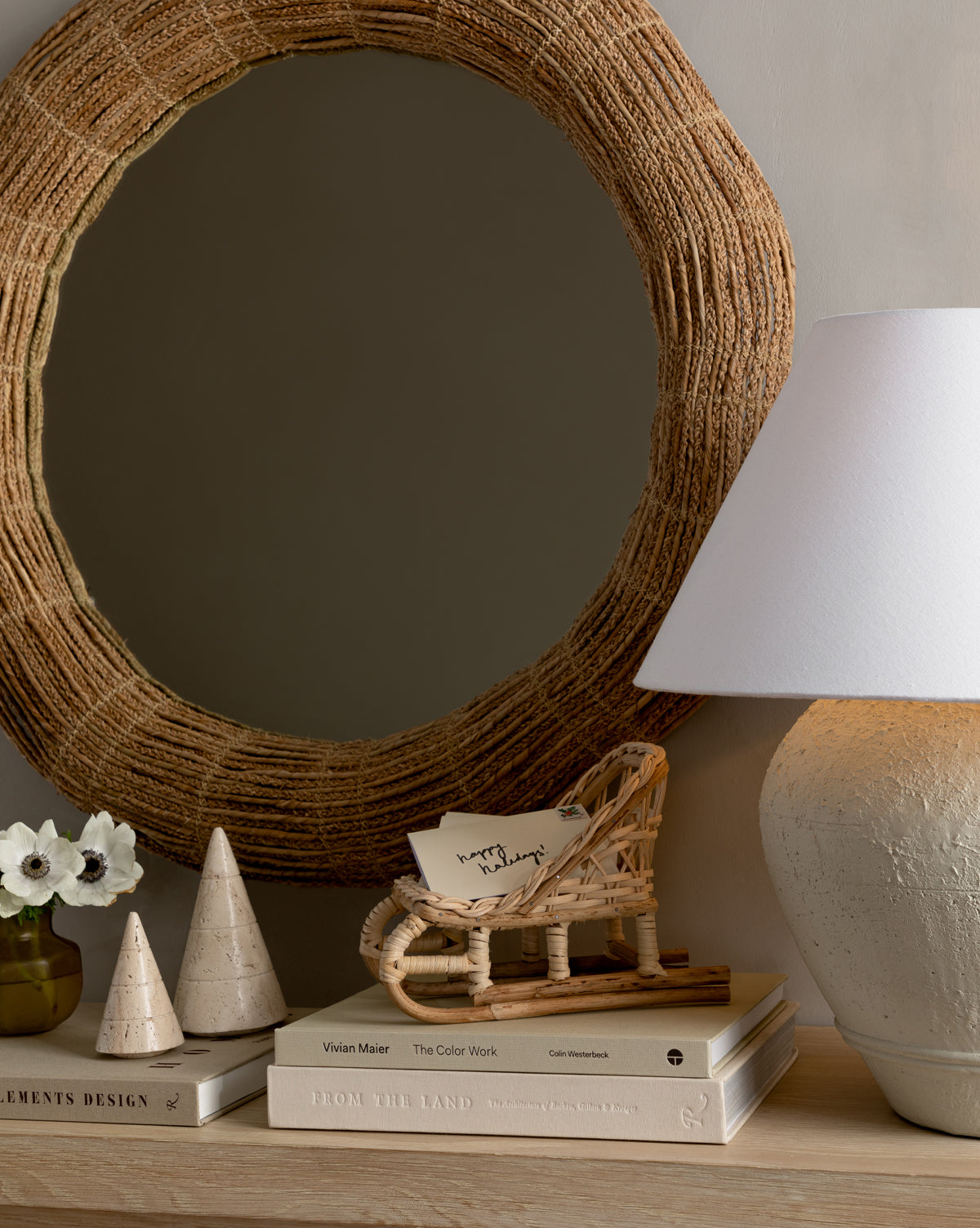 A Woven Rattan Sleigh holding a handwritten note rests on the books, adding a natural touch to your holiday decor, by McGee & Co.