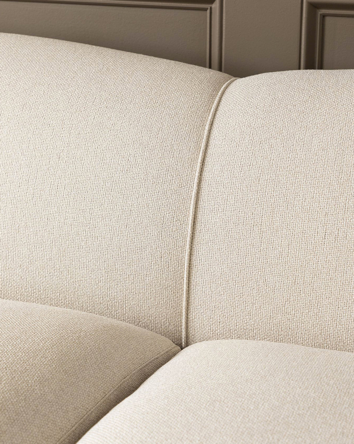 The Rowley Sofa 85 by Rowe Fine Furniture, Inc., showcasing beige fabric upholstery, visible stitching, and textured cushion details against a paneled wall. Customizable fabric options available. McGee & Co.