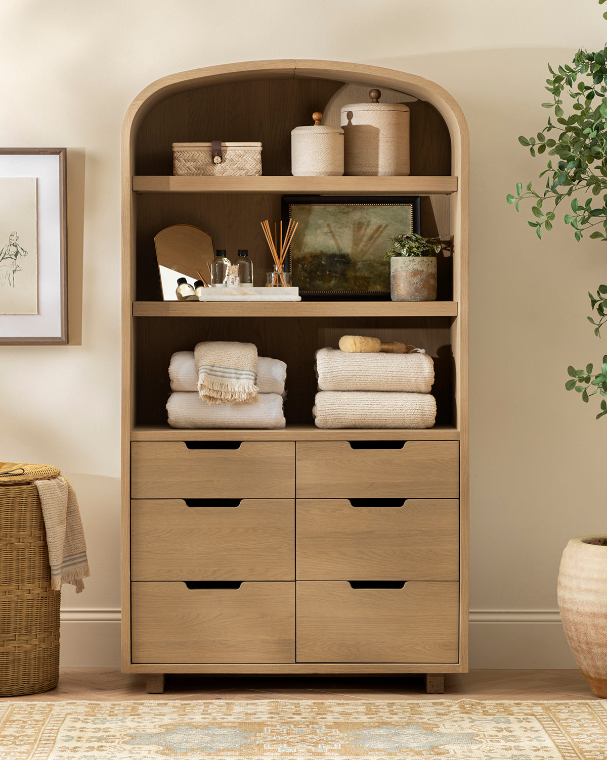 The Burnham Cabinet, featuring open shelves and six drawers, is perfect for organizing towels, baskets, jars, and decor in your dining room. Style it against a beige wall with a plant and framed art for a complete look by McGee & Co.
