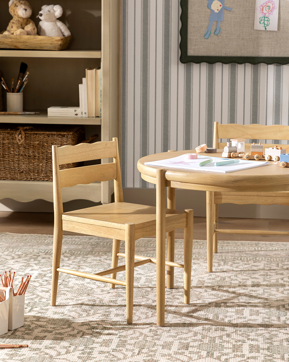 A light wood chair and table with art supplies sit on the Orsino Hand-Knotted Rug in a cozy children’s room, with shelves displaying toys, baskets, and wall art in the background, by McGee & Co.