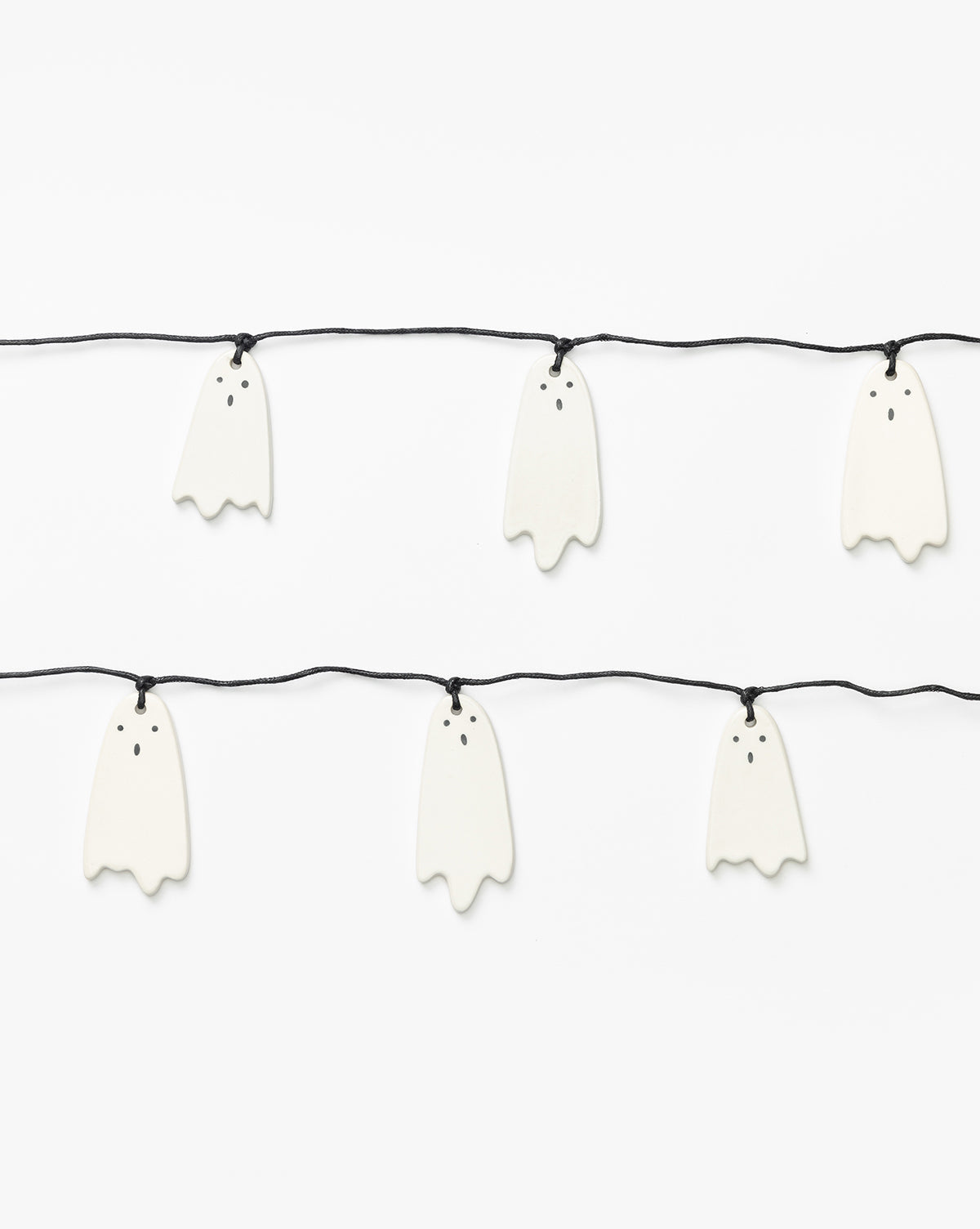 The 3 Ceramic Ghost Garland features cute white ghosts with hand-detailed faces—two black eyes and a round mouth—strung on two black cords against a plain background, making it perfect for charming Halloween decor, by McGee & Co.