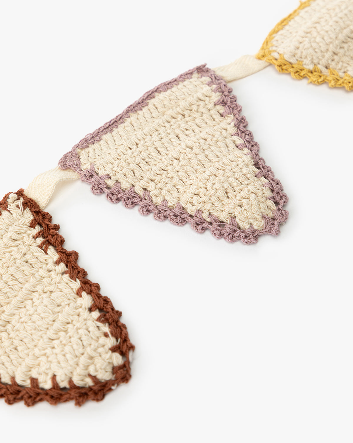Close-up of the 6' Cotton Crocheted Pennant Garland in cream, featuring purple and brown scalloped edges—all hand-woven and linked by a cream string for eco-friendly, charming decor, by McGee & Co.