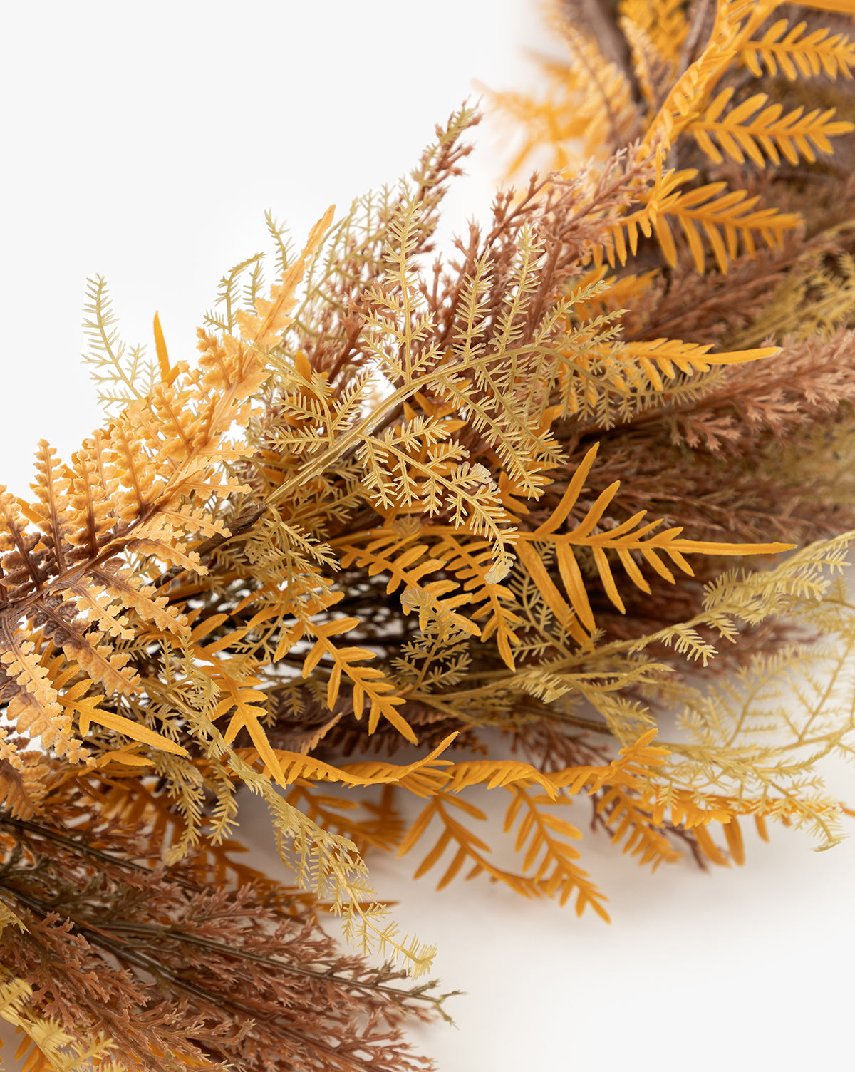 A close-up of the 6 Faux Golden Fern Garland, featuring yellow, orange, and brown hues against a white background—ideal for autumn décor, by McGee & Co.