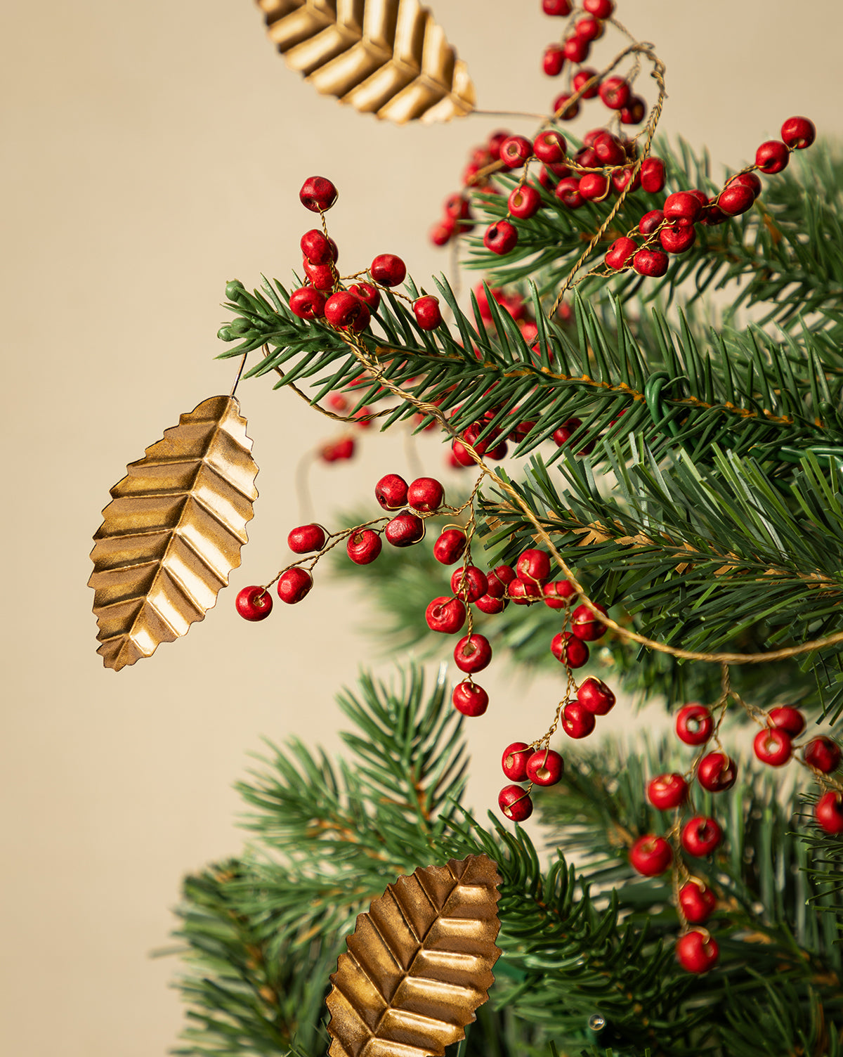 Close-up of the 6' Holly Berry Garland, featuring pine branches, red berries, and gold metallic leaves—perfect for festive holiday décor against a beige background, by McGee & Co.