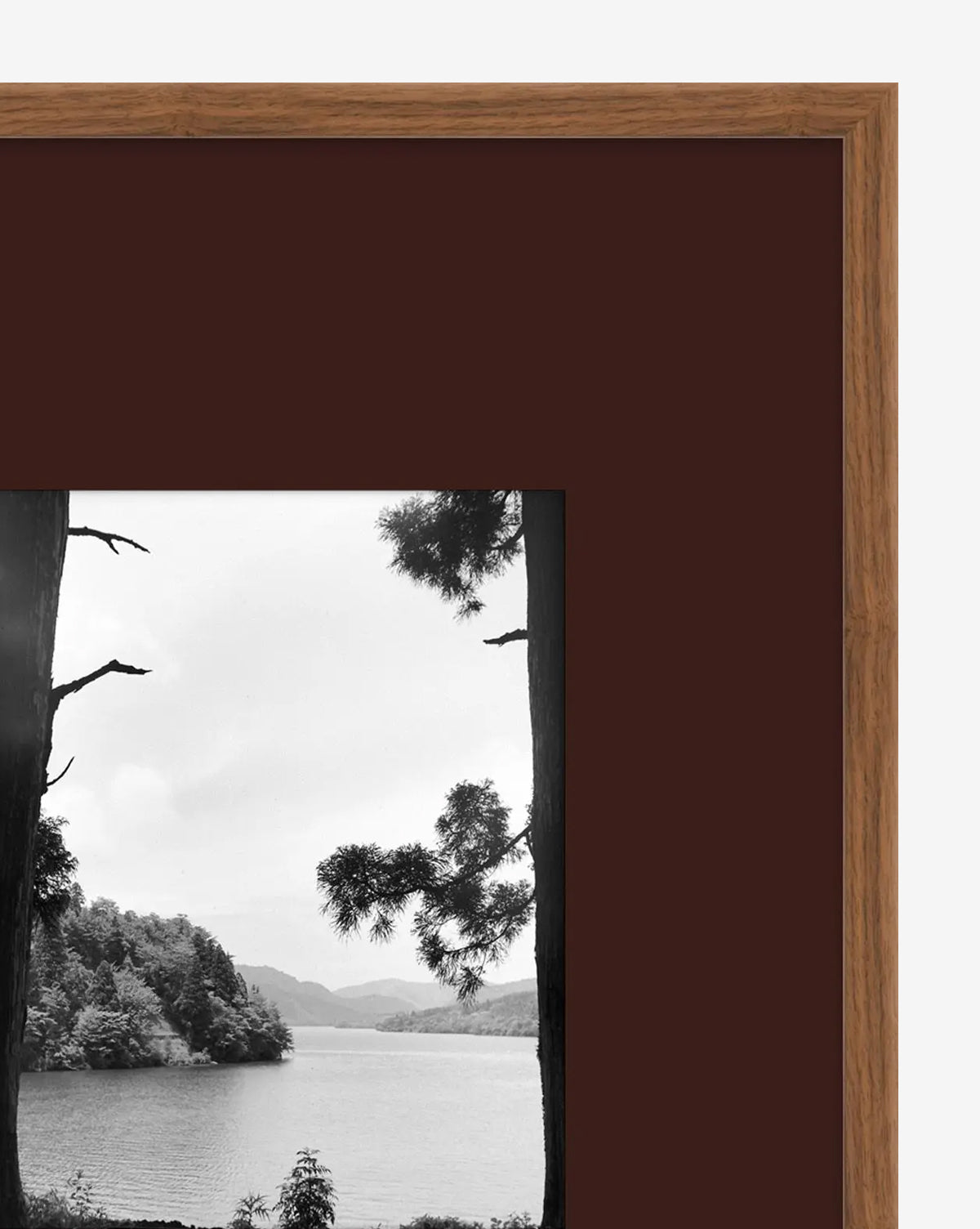 A close-up of A Day in Lake Time III, a framed black-and-white giclée landscape print featuring a lake, trees, and distant hills, set within a wide dark brown mat and an elegant wooden frame by McGee & Co.