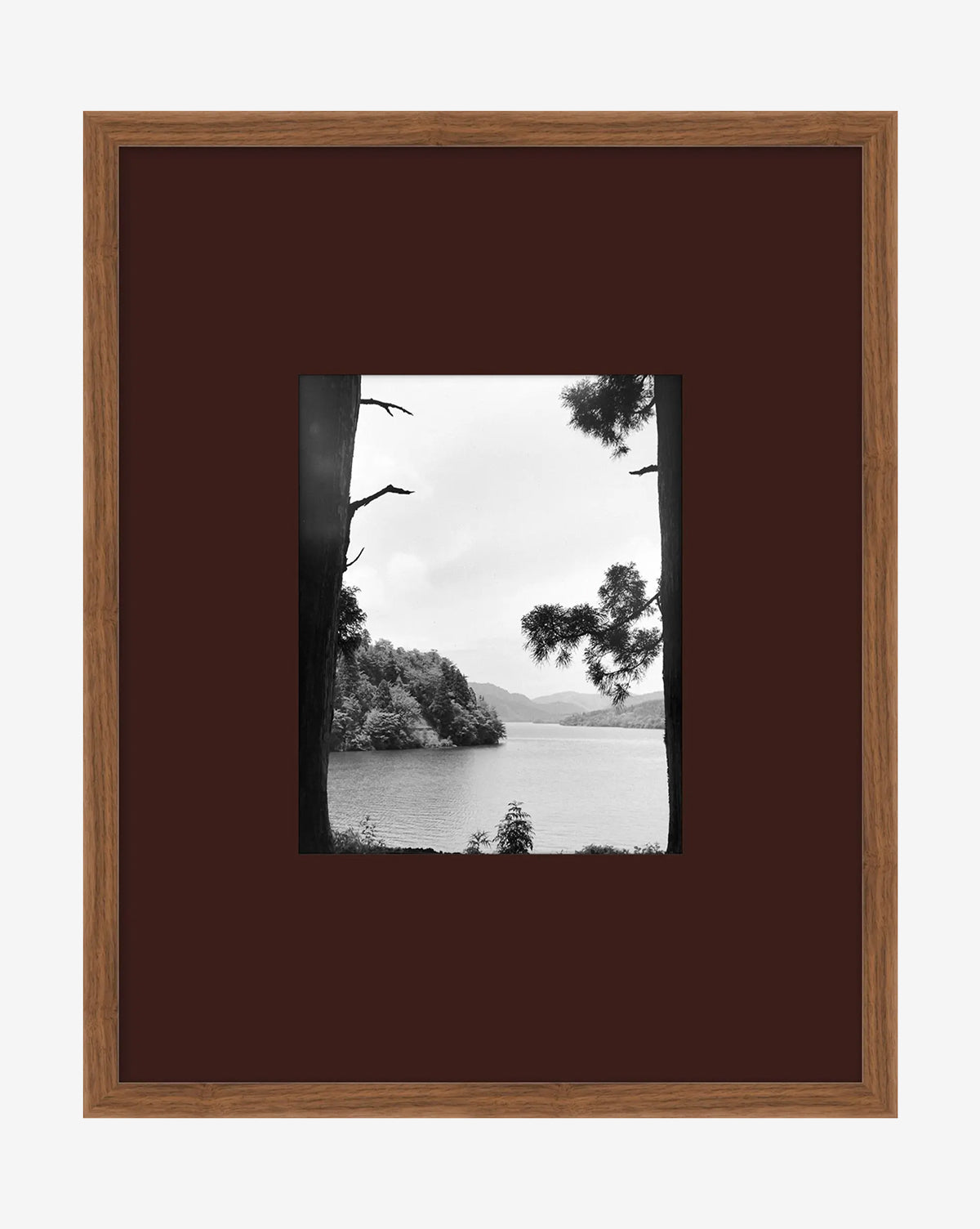 A Day in Lake Time III is a black-and-white giclée print depicting a tranquil lake with trees and distant hills, beautifully presented in a brown wooden frame with a dark mat—an elegant piece of lake wall art, by McGee & Co.