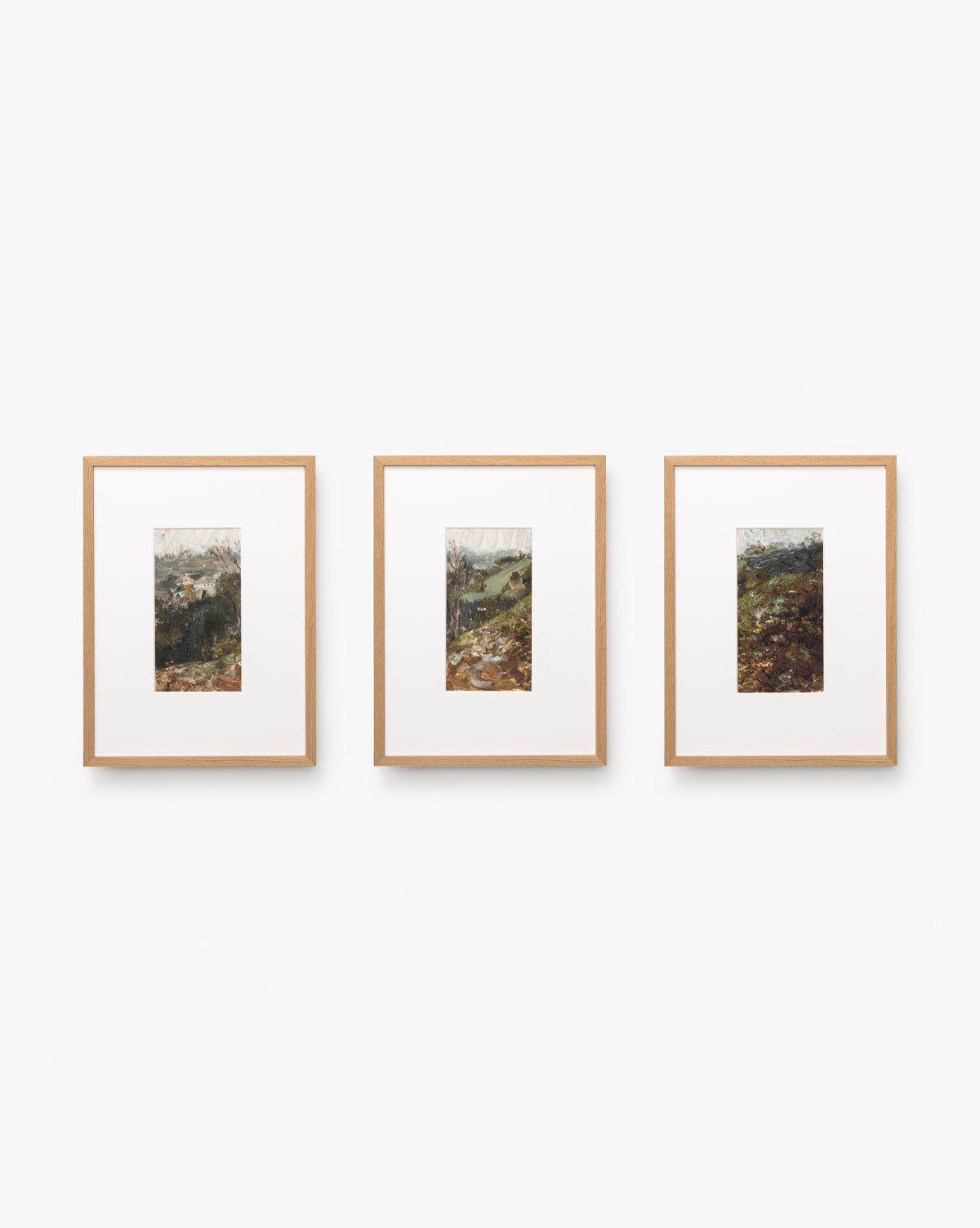 Three A River Runs Through framed abstract landscapes with light wood frames are centered on a white wall. Each features natural scenery in earthy tones, arranged side by side for a striking horizontal display by McGee & Co.