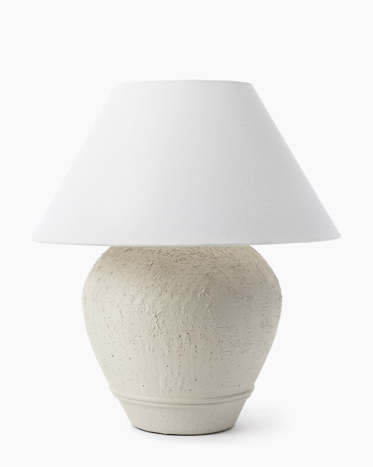 The Abbott Ceramic Table Lamp features a textured off-white ceramic base with a wide, round shape and is topped with a simple white linen shade, shown against a plain white background by McGee & Co.