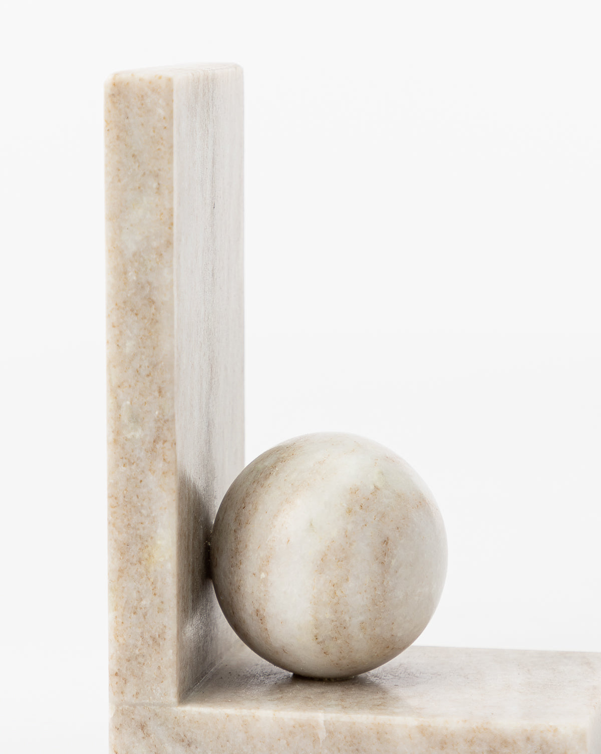 The Adar Marble Bookends (Set of 2) feature smooth, round marble spheres paired with perpendicular marble slabs. Each bookend showcases subtle natural stone patterns, creating a striking modern look against a white background.