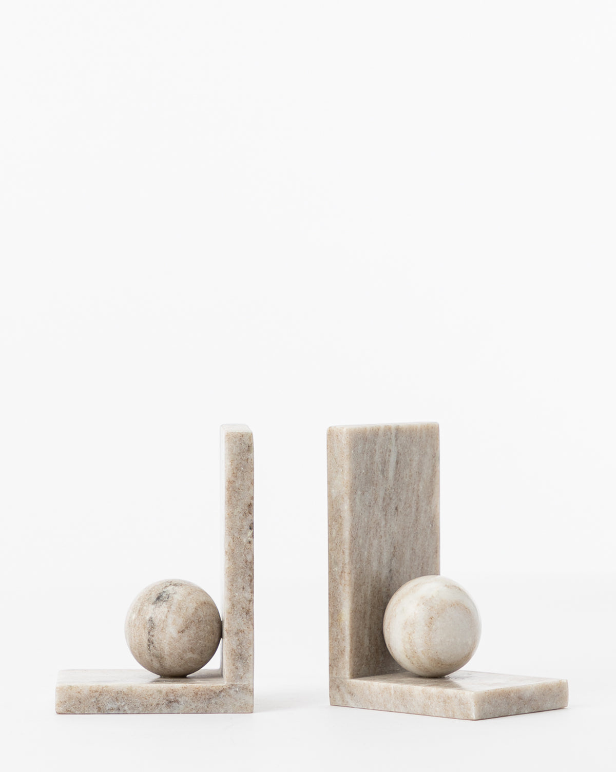 The Adar Marble Bookends (Set of 2) feature an L-shaped design with a spherical stone base, crafted from light-toned marble with subtle veining. They are displayed side by side against a plain white background.