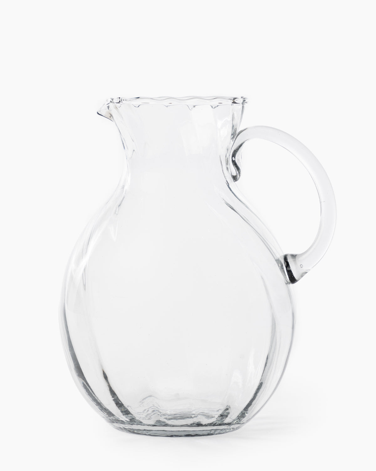 The Adderley Pitcher, made of clear mouth-blown glass with a rounded body, small spout, and curved handle, is displayed against a plain white background by McGee & Co.