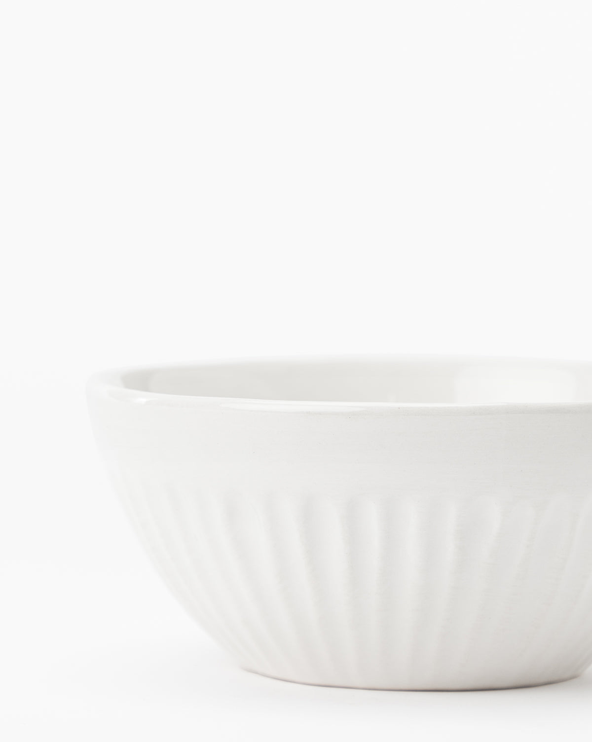 The Adele Bowl, featuring fluted detailing and a timeless white ceramic design, sits on a white surface against a plain white background by McGee & Co.