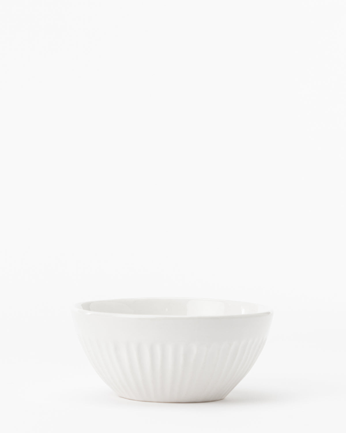 The Adele Bowl, a small white ceramic piece with a subtle ridged texture, sits on a plain white background, highlighting its timeless design, by McGee & Co.