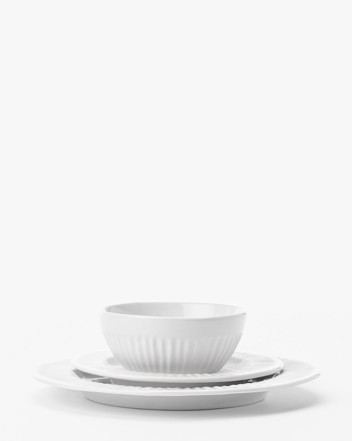 A white bowl is stacked on an Adele White Salad Plate (Set of 4), arranged atop a larger plate to showcase timeless dinnerware against a plain white background, by McGee & Co.