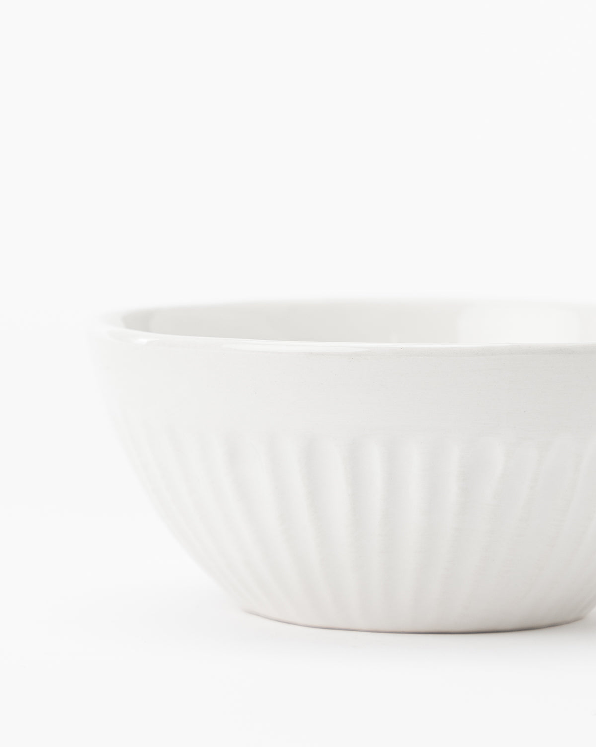 A close-up of the Adele Bowl (Set of 4), featuring a ribbed white ceramic finish and timeless design, positioned slightly off-center on a plain white background, by McGee & Co.