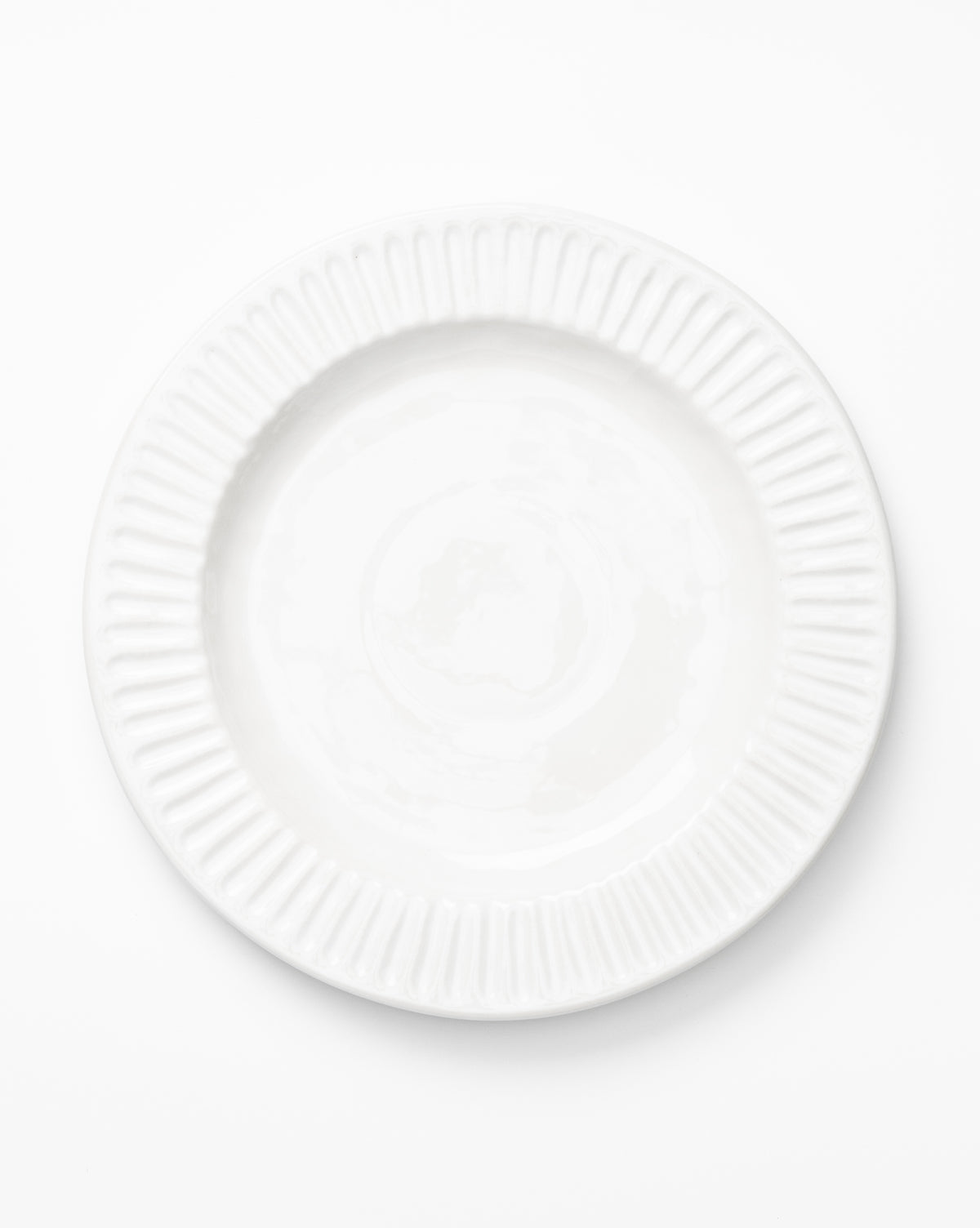 Photographed from above against a white background, a single empty plate is centered in the image, by McGee & Co.