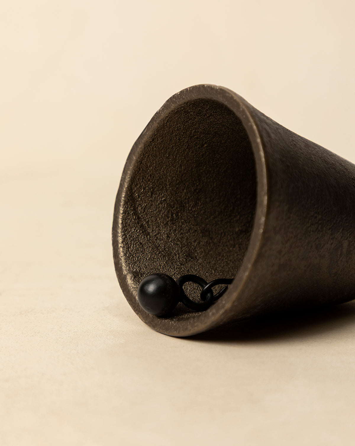 Aged Brass Bell lying on its side on a light beige surface reveals the inside and clapper, capturing vintage charm ideal for holiday decor, by McGee & Co.