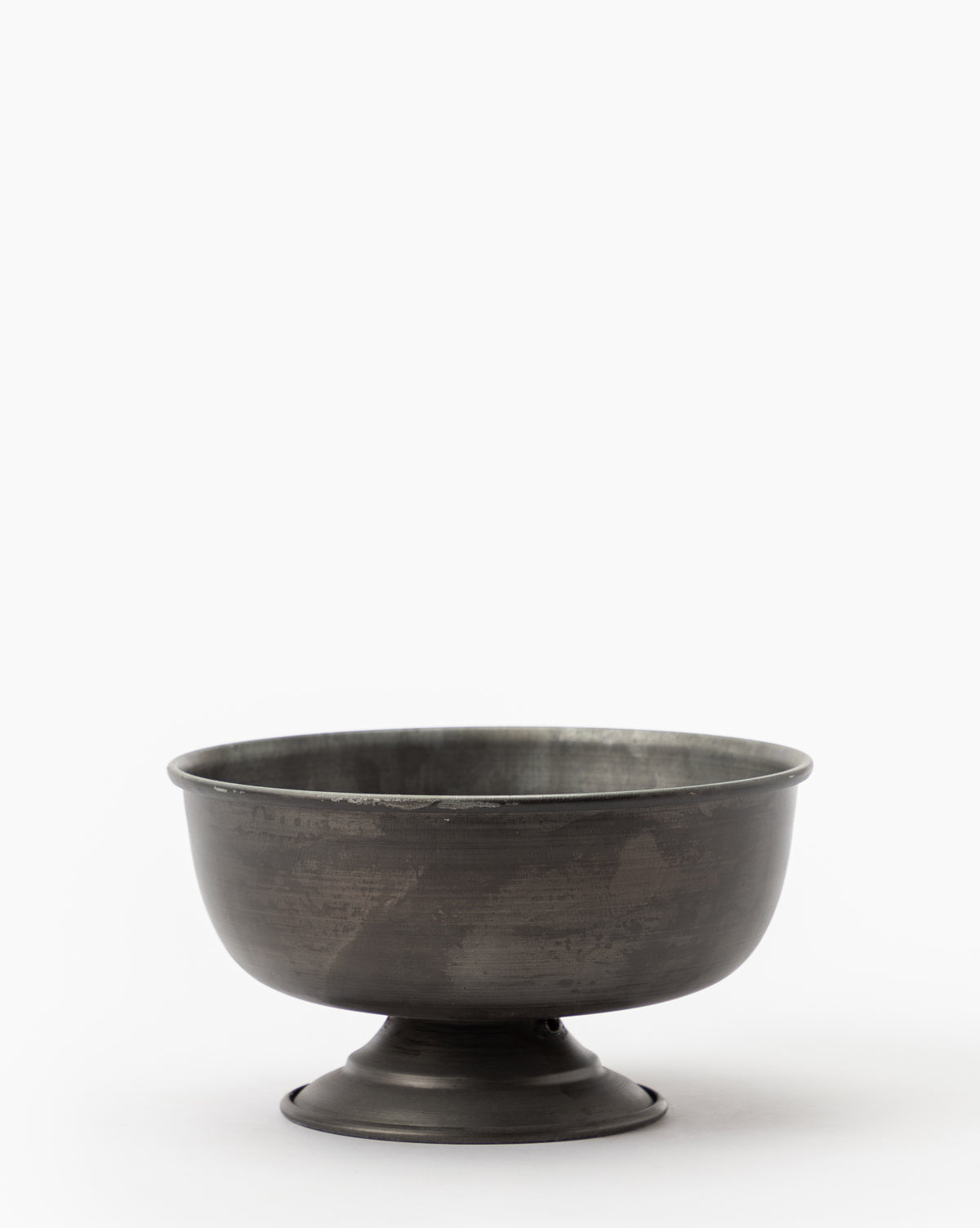 The Aged Iron Compote is a dark metal bowl with a wide rim and short pedestal base, ideal for displaying floral arrangements against a plain white background.