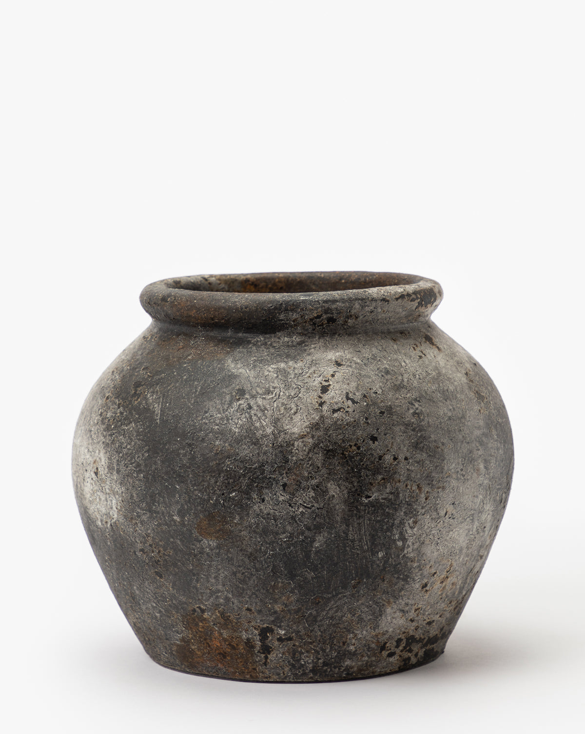 The Aged Terracotta Jar features a round, weathered design with a dark gray finish, wide body, narrow base, and slightly flared rim, creating striking textured home decor against a plain white background.