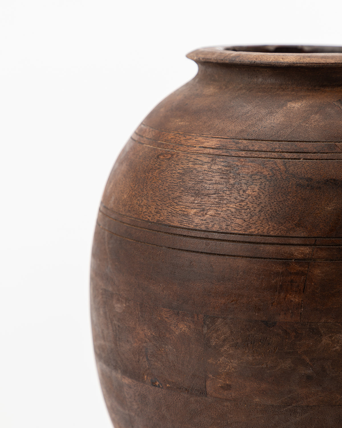 A close-up of the Aged Wood Vase, featuring a dark brown textured ceramic finish and timeless etched design, set against a plain white background. Only the upper right side of the vase is visible in the image.
