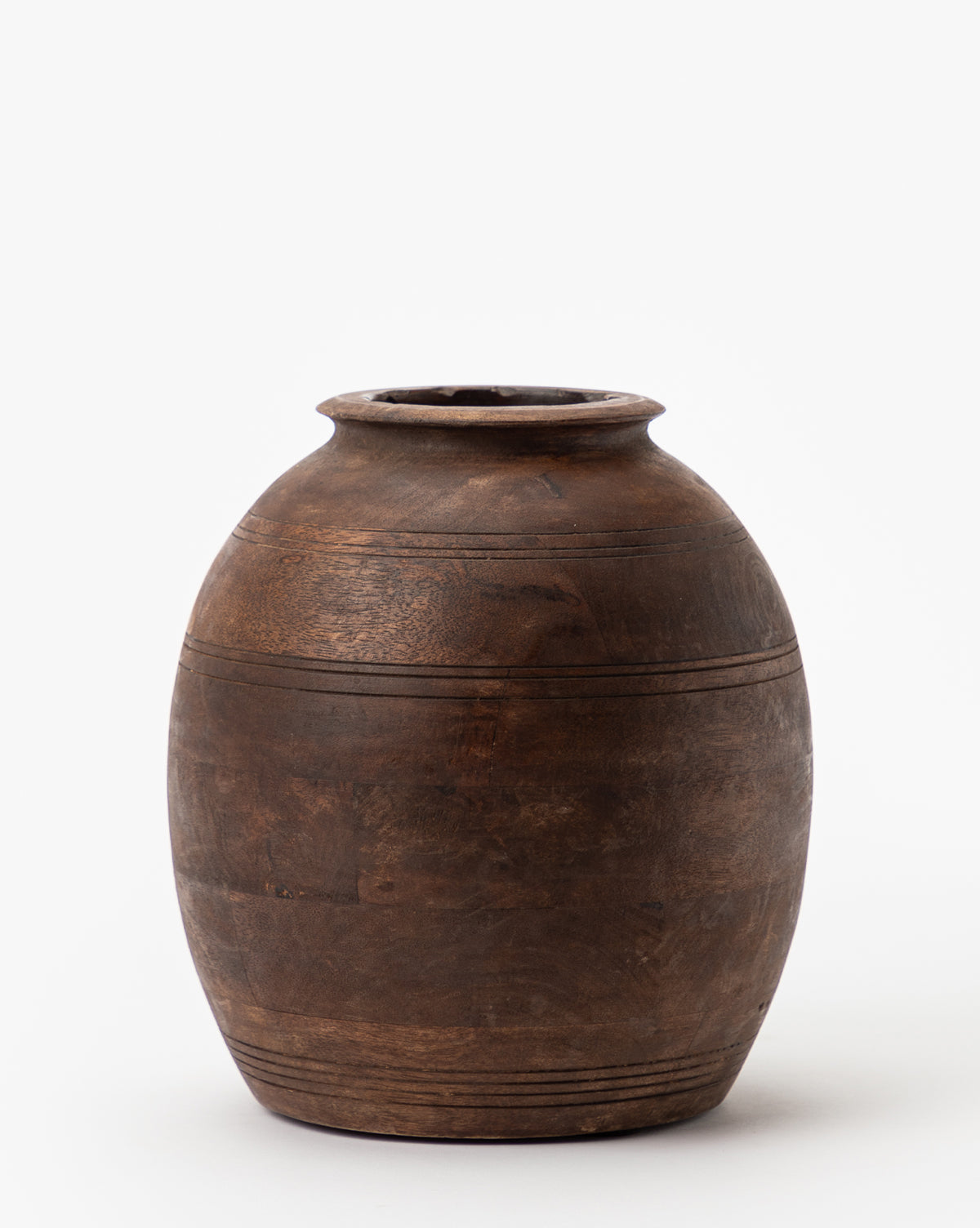 The Aged Wood Vase features a round, dark brown body with a wide base, narrow neck, and small opening. Subtle horizontal carved lines create an elegant etched design on its smooth surface, all highlighted against a white background.