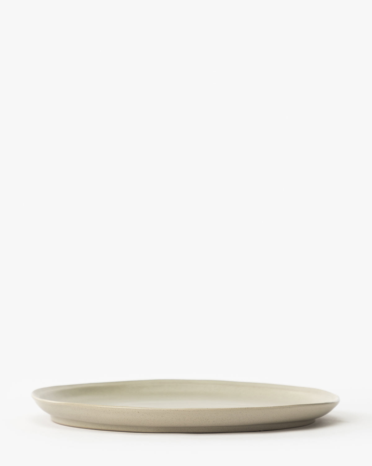 The Aiden Soft Gray Dinner Plate is simple and round with a slightly raised edge, shown against a plain white background, by McGee & Co.