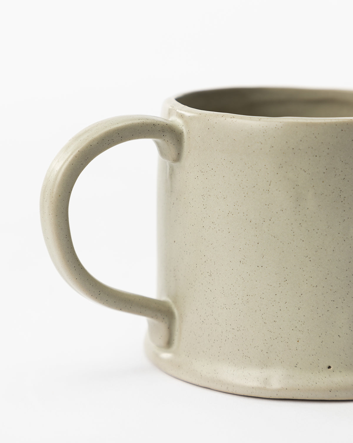 A close-up of the Aiden Soft Gray Mug with a curved handle, displayed against a plain white background. Only half of the elegant beige ceramic mug is visible, by McGee & Co.