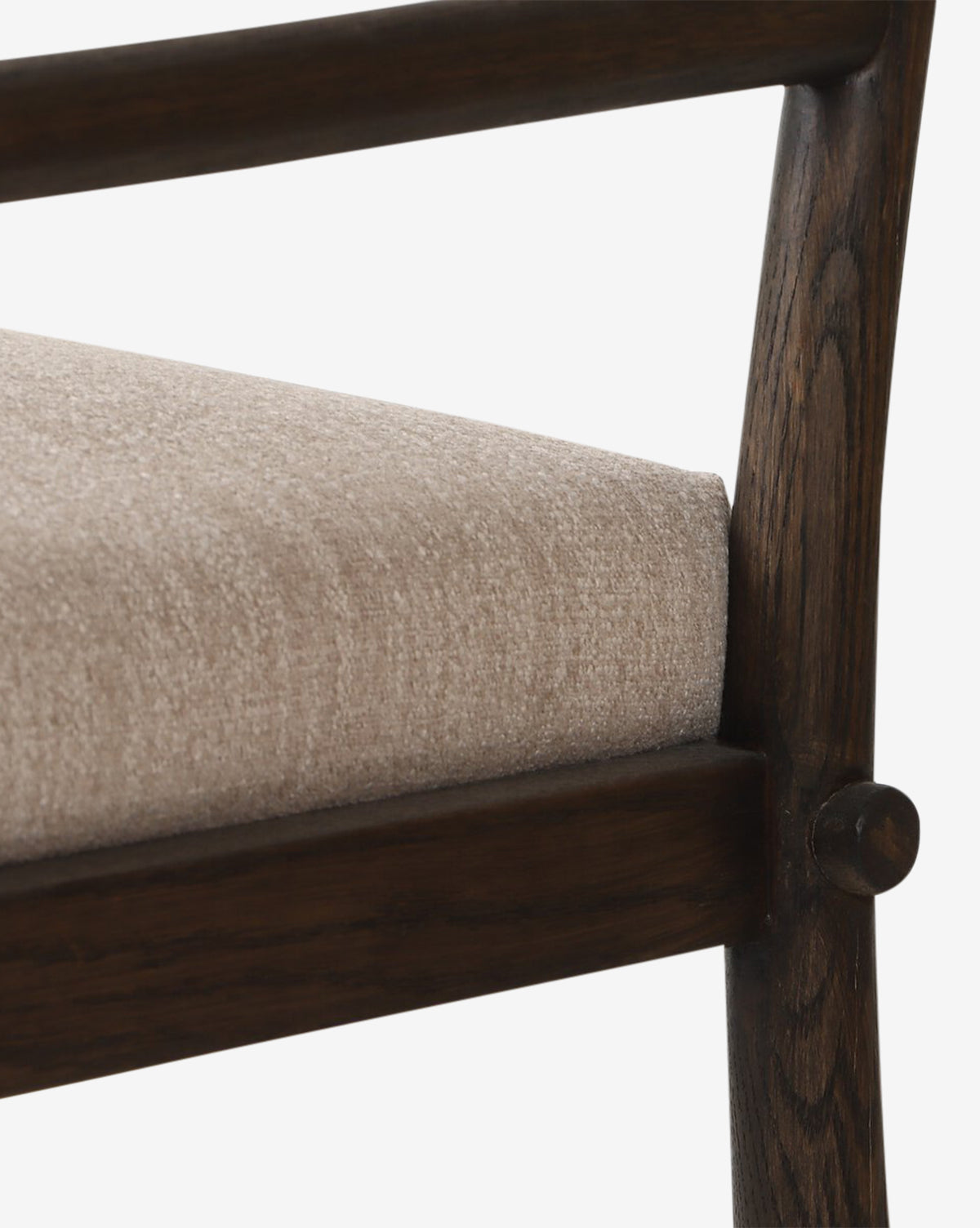 Close-up of the Ailsa Dining Chair, a modern piece with a dark brown oak frame and cushioned beige seat, showing the seat, armrest, and leg details against a white background by McGee & Co.