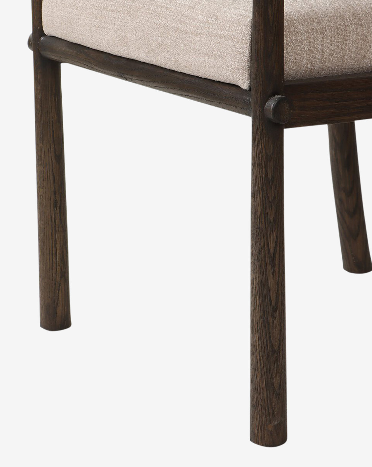 Close-up of the Ailsa Dining Chair’s dark wooden legs and frame with a beige upholstered seat. This modern chair showcases a simple, elegant design set against a plain white background, by McGee & Co.