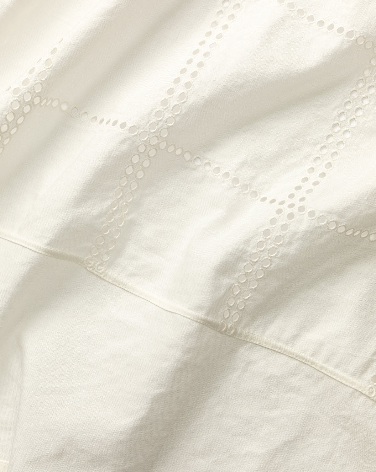 Close-up of Albany Shower Curtain’s white linen-cotton fabric with small circular cutouts forming grid lines, giving a soft, textured look—ideal for adding elegance to your bathroom decor, by McGee & Co.