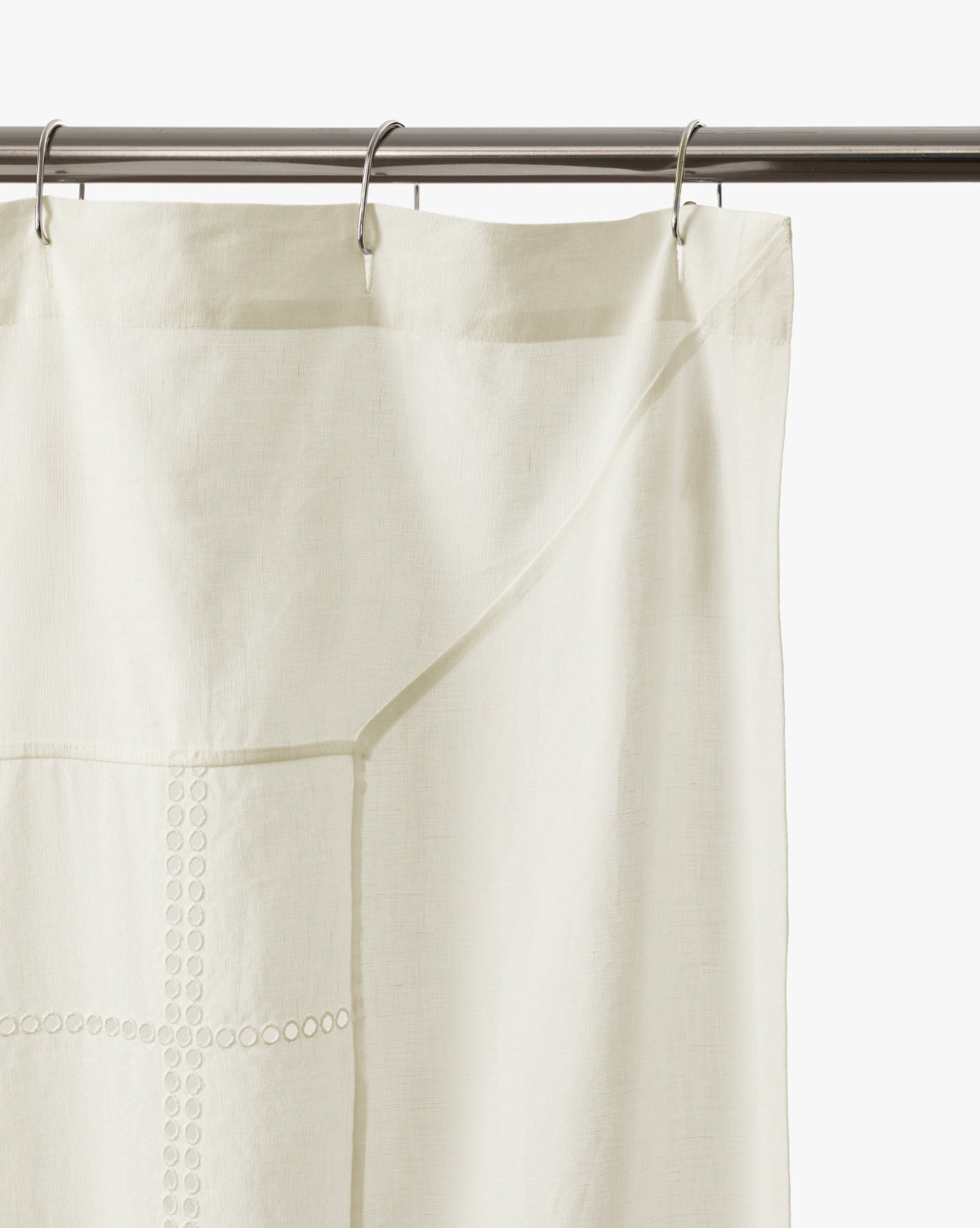 The Albany Shower Curtain in off-white linen-cotton hangs from a silver rod with metal rings, featuring subtle top embroidery—an elegant addition to your bathroom decor, by McGee & Co.
