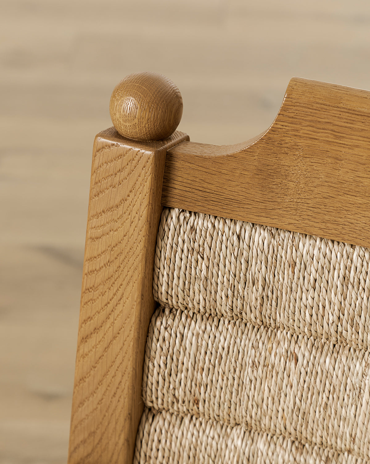 Close-up of the Alberta Lounge Chair’s upper corner, showing a rounded finial and woven wicker backrest, with a soft, light background by McGee & Co.