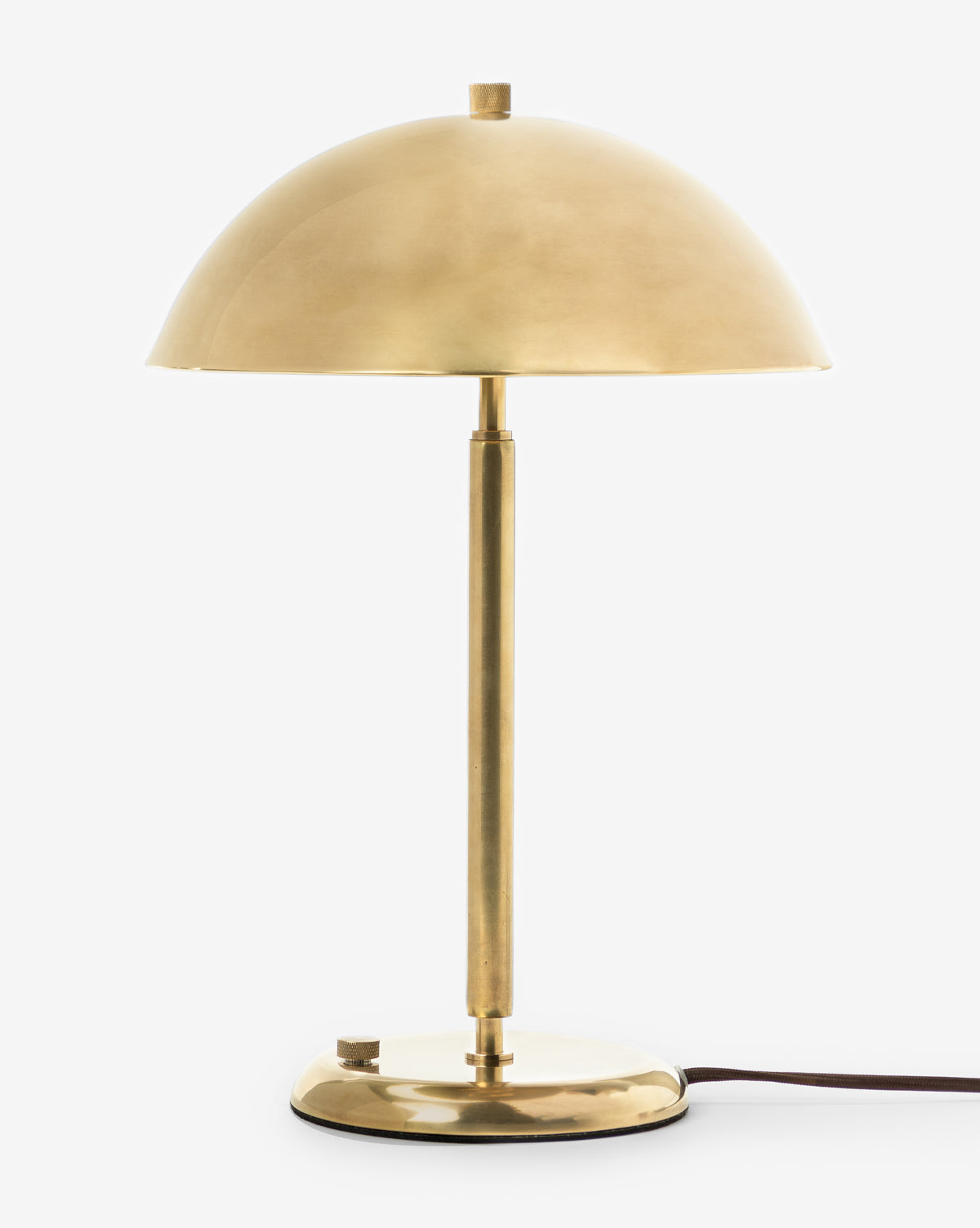 The Aldorno Desk Table Lamp features a brass finish, dome-shaped shade, slender stem, and round base against a plain white background. A black power cord extends from the base—ideal as a modern accent for any space, by McGee & Co.