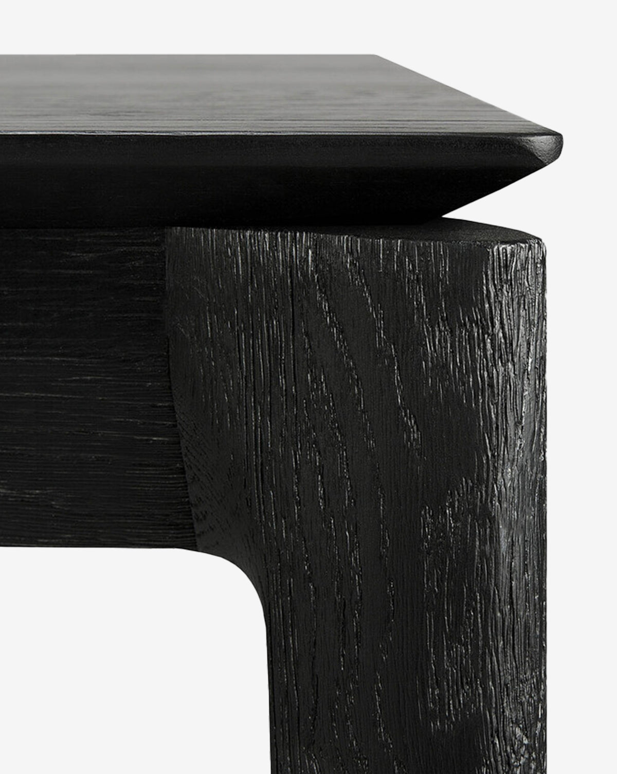 Close-up of the Alec Dining Table’s black wooden corner highlights its textured grain and sturdy build, making it a stylish addition to any dining room, by McGee & Co.
