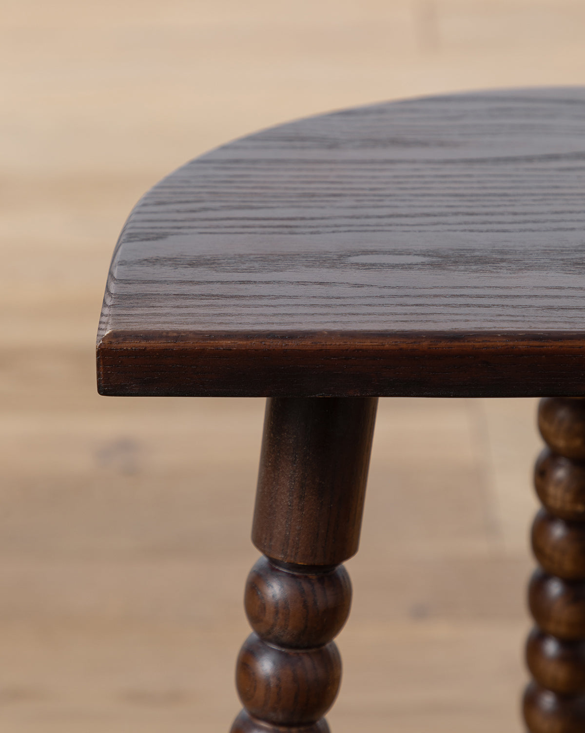Close-up of the Alice Wood Stool, crafted in ash with polished, rounded edges and beaded, turned legs, set on a light wooden floor for a vintage-inspired look, by McGee & Co.