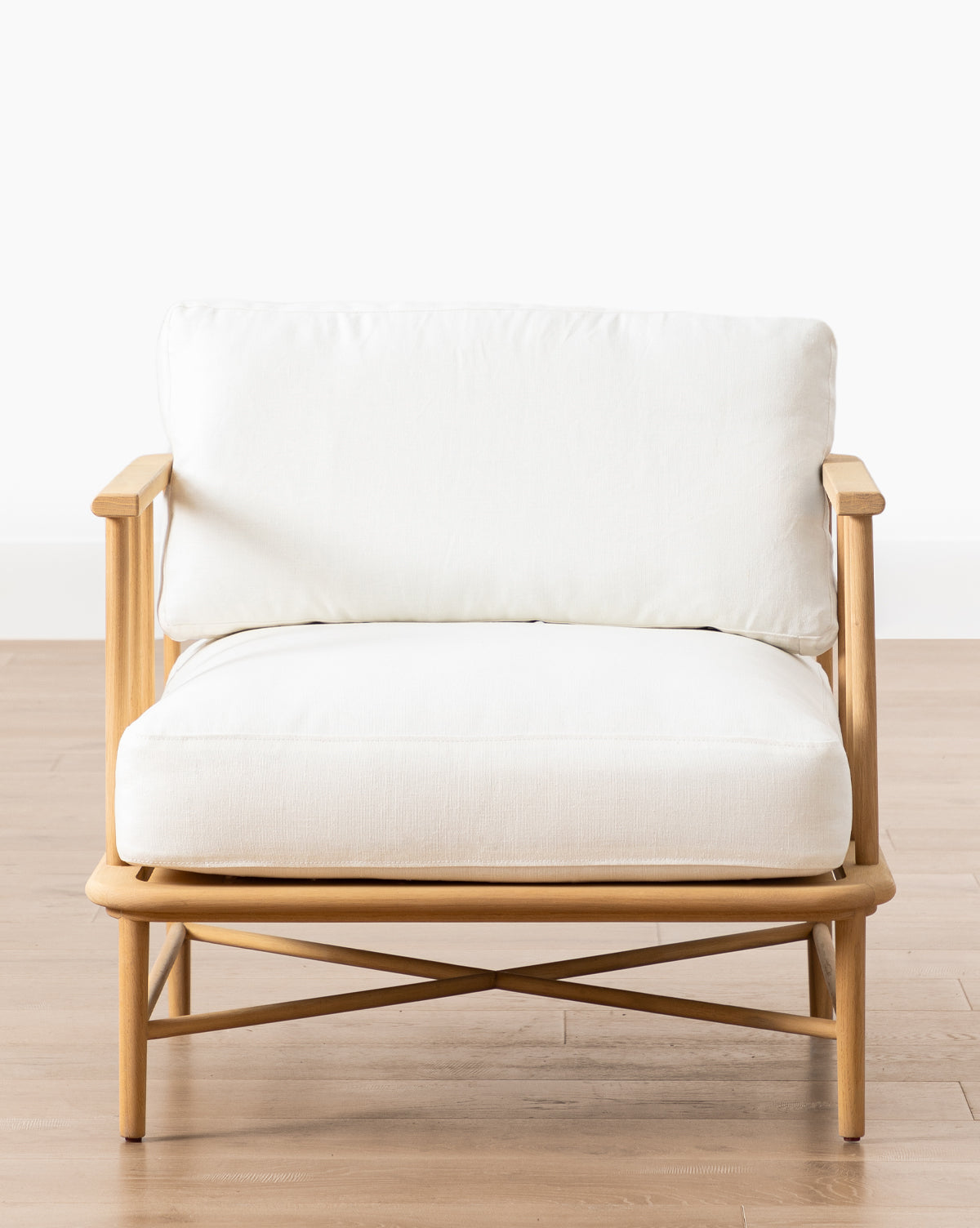 The Alma Lounge Chair features a light solid oak frame with white cushioned seat and backrest, set on a light wood floor against a plain white background—a stylish contemporary accent for any space by McGee & Co.
