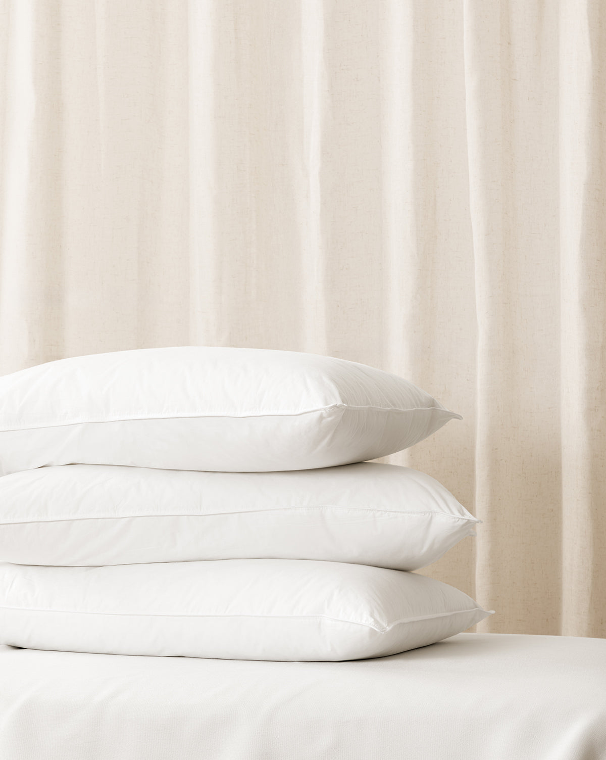 A stack of white, plush pillows with a soft focus background from McGee & Co.