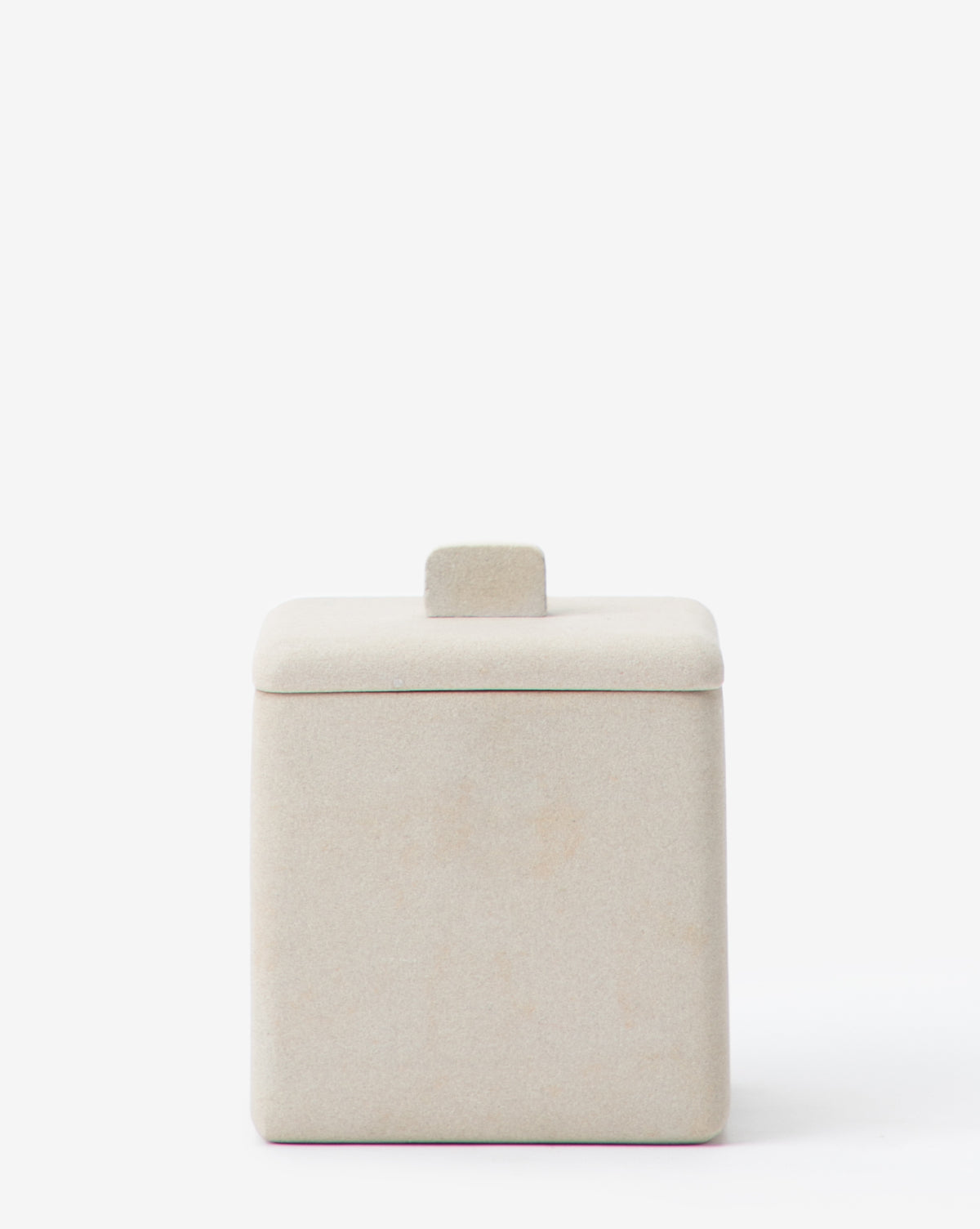 A beige, square ceramic container with a tab handle and matching lid from the Amada Sandstone Bath Collection brings an organic touch to your bathroom, shown against a plain white background.