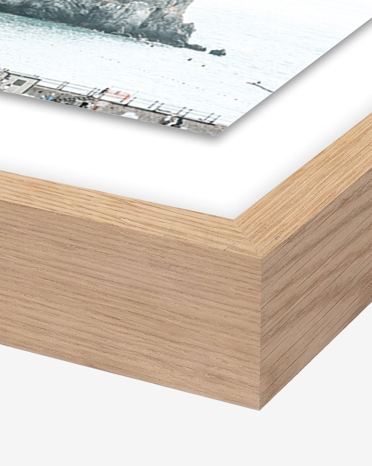 Close-up of a white oak frame corner with mitered joint, displaying part of Amalfi Overexpose by Natalie Obradovich—a photograph of the Amalfi coastline with water and rocks.