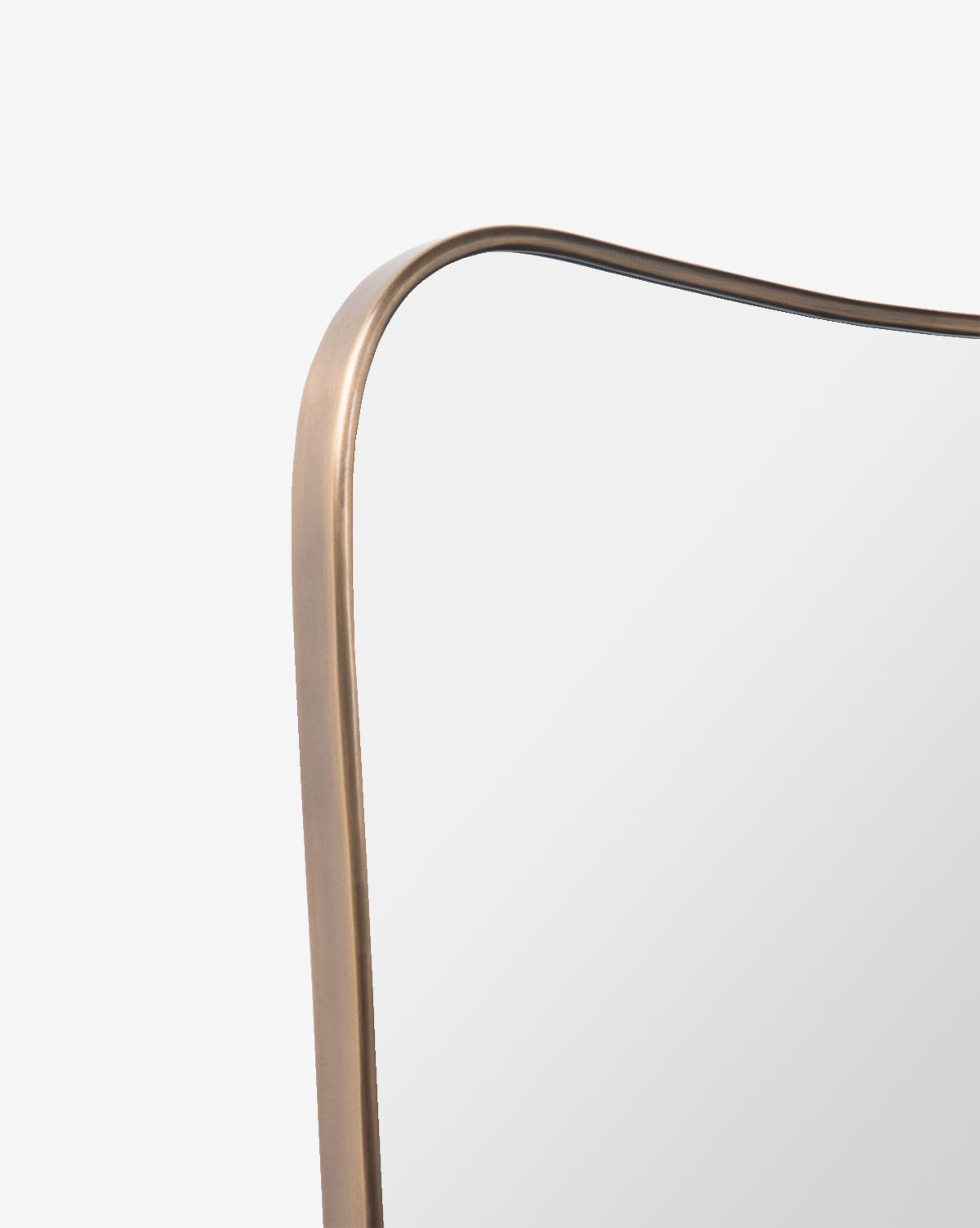 Close-up of the top corner of the Anastasia Wall Mirror, featuring a rounded edge and thin metallic frame in a bronze or gold finish, set against a plain white background by McGee & Co.