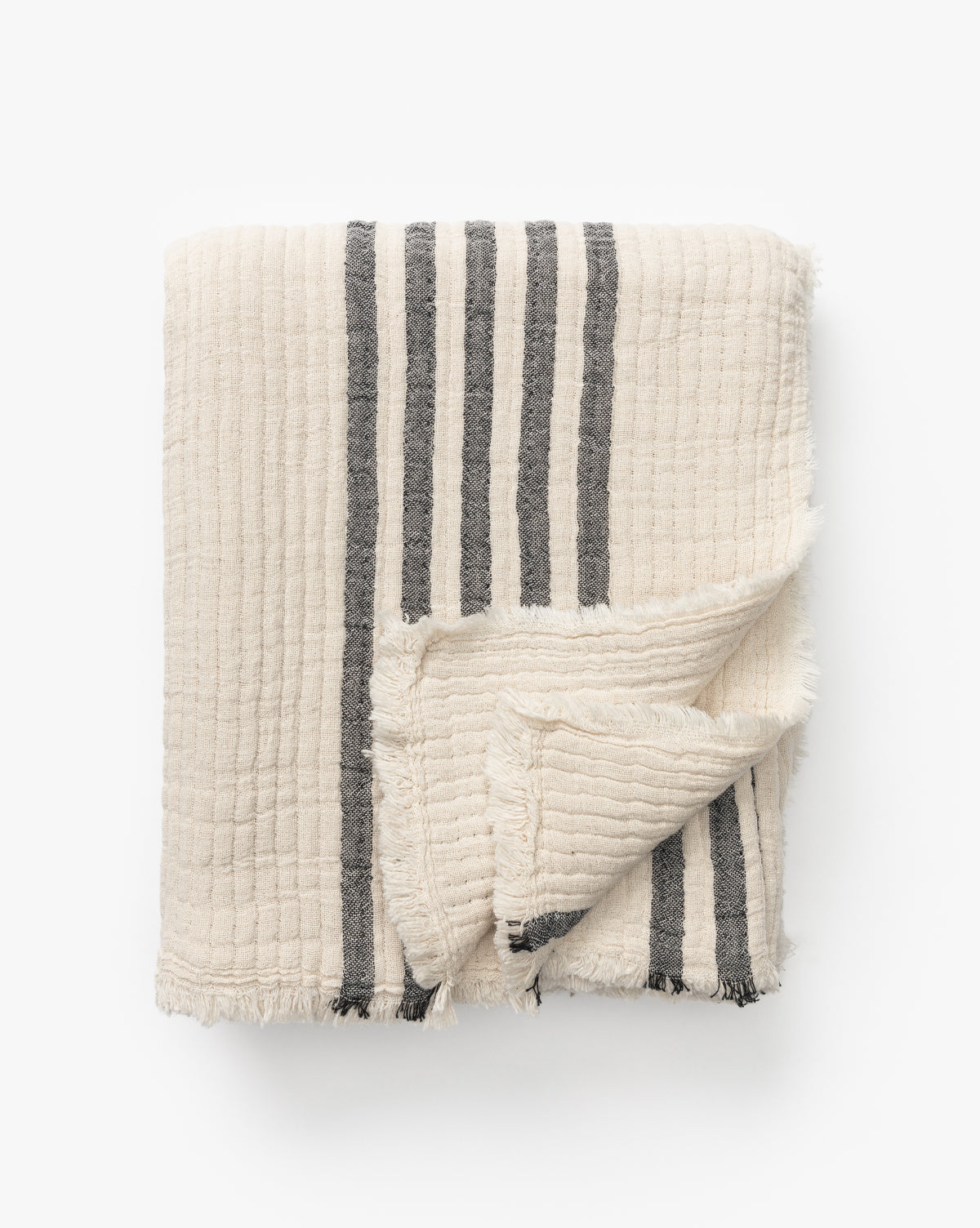 The Anneliese Striped Throw by Creative Co-op features cream cotton with a grid texture, dark gray vertical stripes, and fringed edges—an elegant piece for luxury home decor, shown on a white background by McGee & Co.