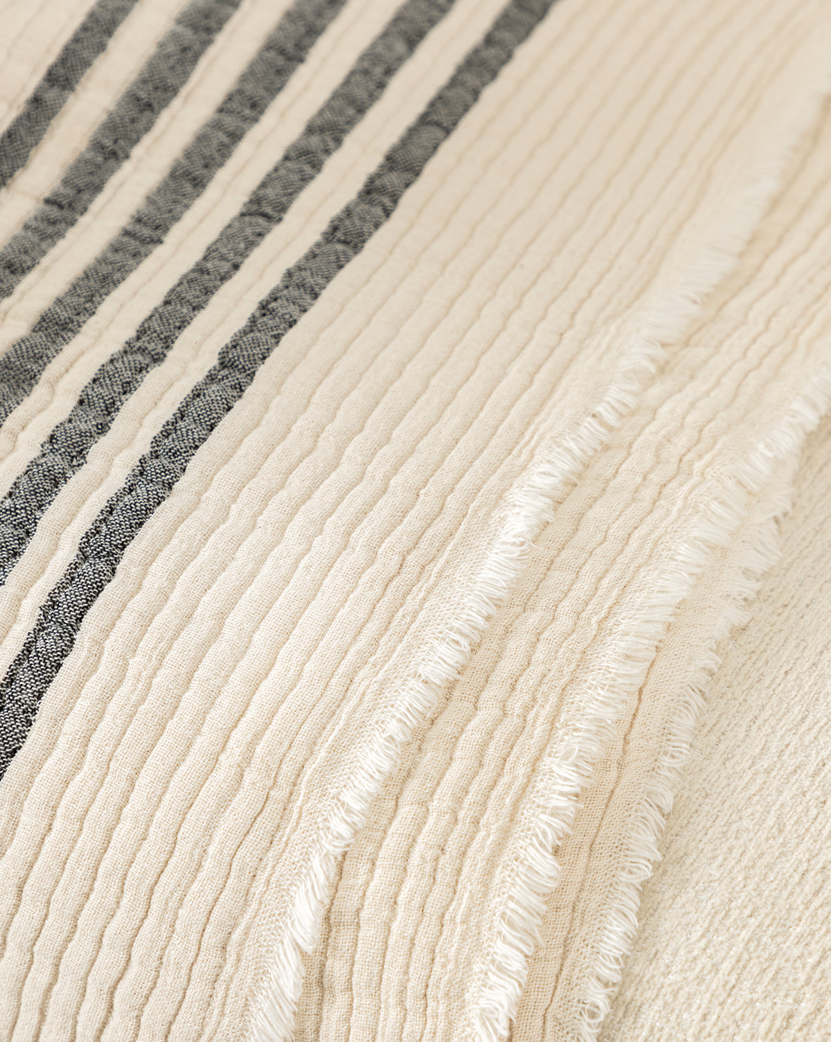 The Anneliese Striped Throw by Creative Co-op features cream-colored cotton with raised ribbed lines, two dark gray stripes, and fringed seams—an elegant accent for luxury home decor from McGee & Co.