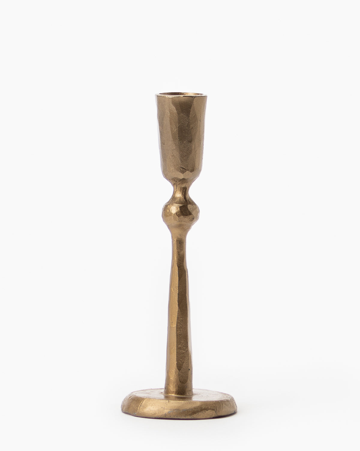The Antique Brass Taper Candle Holder features a hammered texture, narrow stem, and round base, standing elegantly against a plain white background.