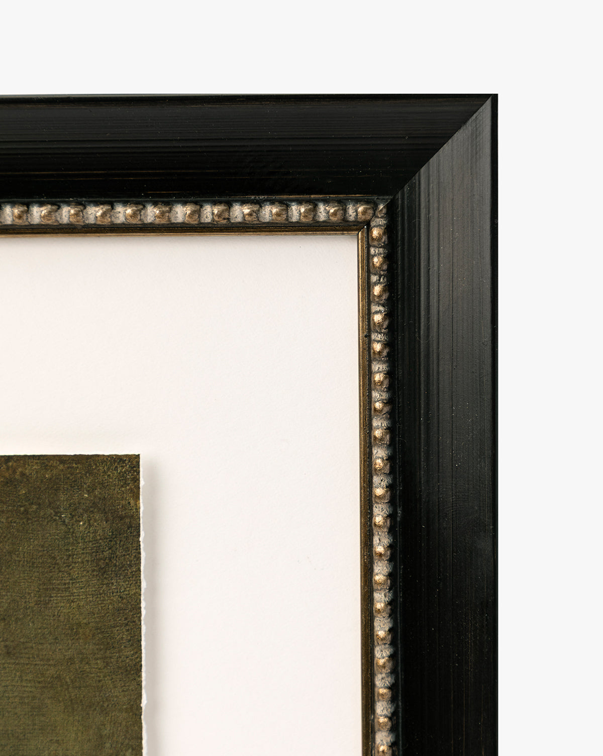 Close-up of the top right corner of a black wooden picture frame with beaded detailing and a white mat, showcasing the edge of Antique Flower Vase green-toned vintage-inspired wall art, by McGee & Co.