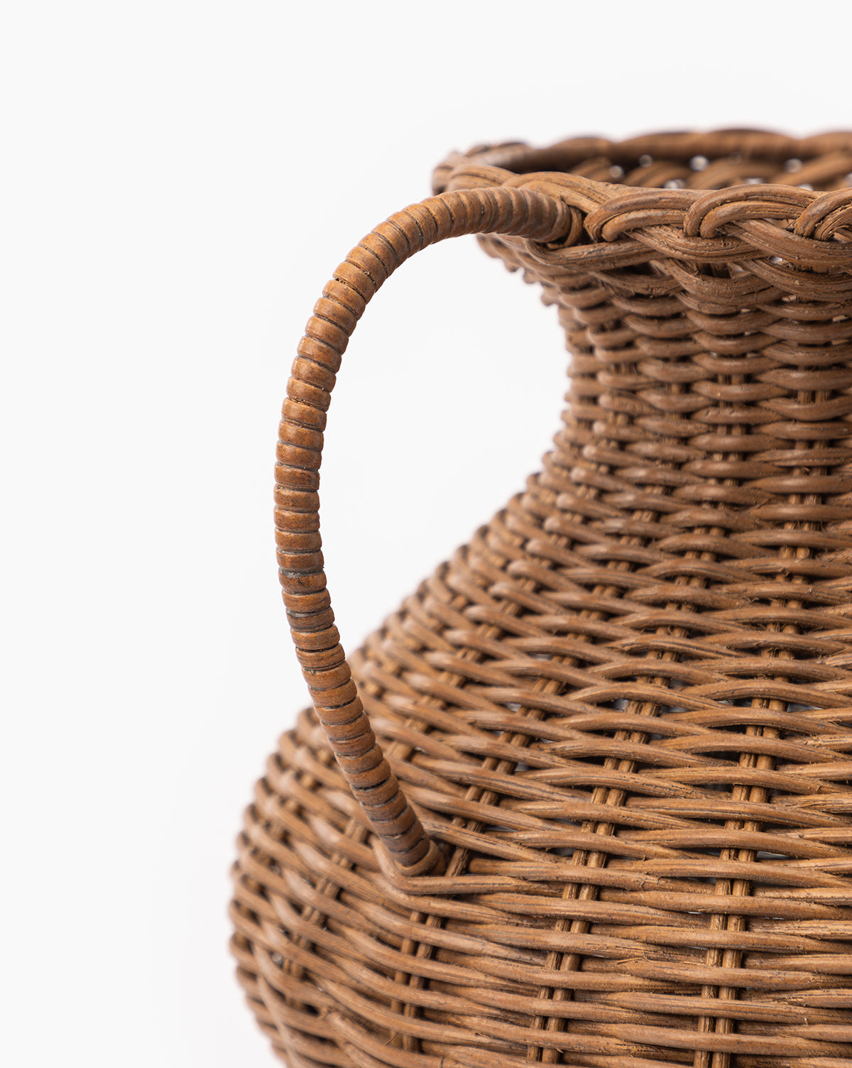 Close-up of the Antonia Woven Vase, featuring a curved handle and wide, rounded body with detailed wicker texture, reminiscent of rattan, set against a white background.