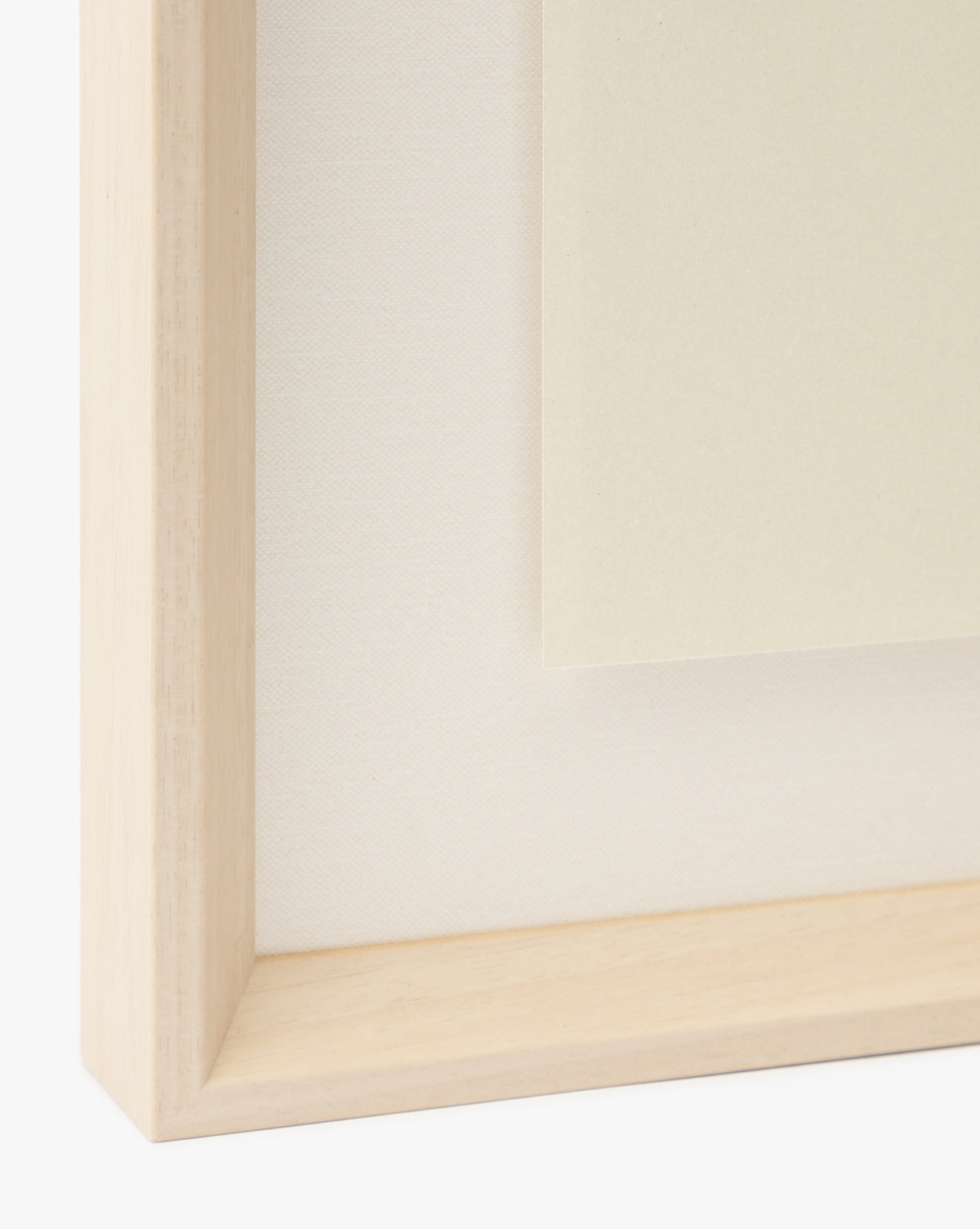 Close-up of a light wooden frame corner with a beige canvas and pale card layered on top—ideal for displaying the Apple Collage as a charming giclee print in a childrens room, by McGee & Co.