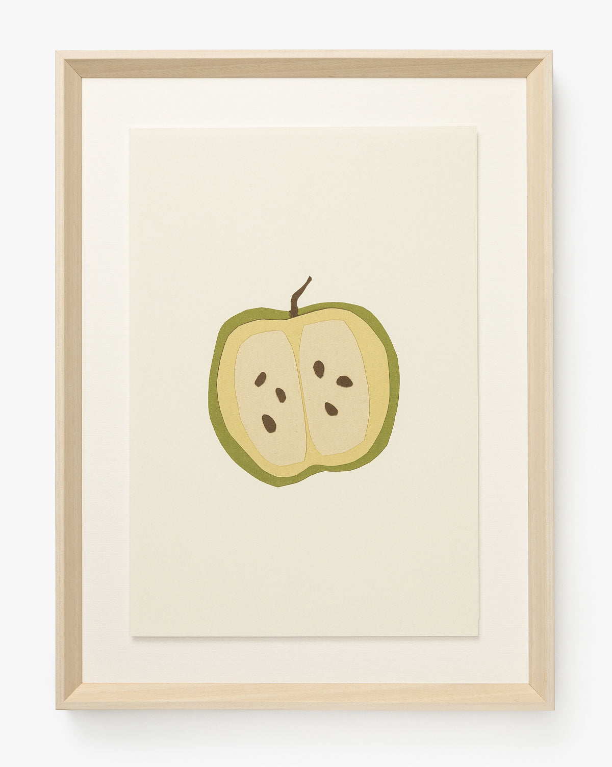 Apple Collage: Minimalist giclée print of a halved green apple with seeds on a plain background. Displayed in a light wood frame with white mat—perfect for adding brightness to a child’s room, by McGee & Co.