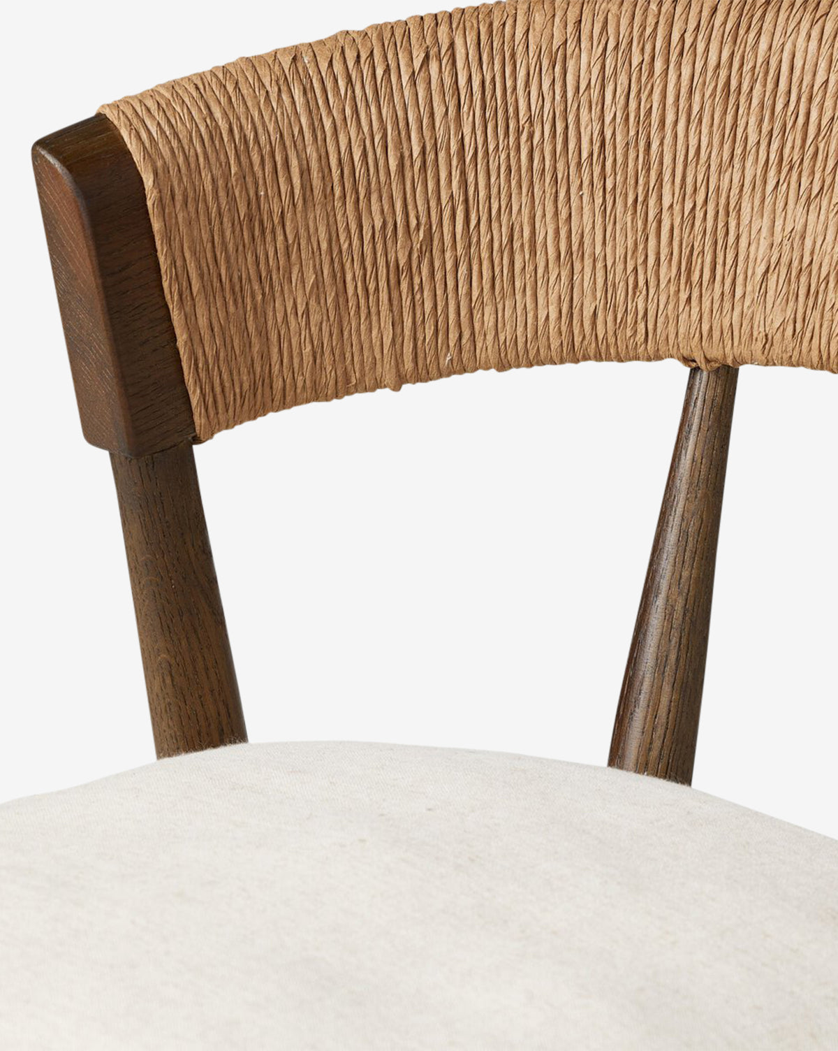 Close-up of the Four Hands Ardent Stool, showcasing a solid oak frame with a curved woven backrest and off-white cushioned seat. The dark wood finish adds elegance—ideal for a kitchen bar. Plain white background. McGee & Co.